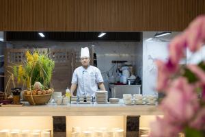 a chef standing behind a counter in a kitchen at Miracle Luxury Nha Trang in Nha Trang