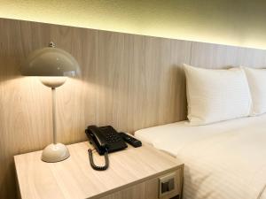 um telefone numa mesa ao lado de uma cama em Green Hotel - Tea Way em Taichung