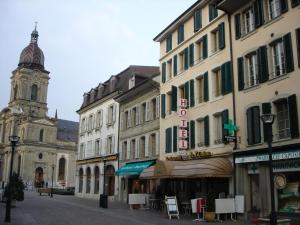 uma rua da cidade com edifícios e uma torre do relógio em Hotel de Savoie em Morges