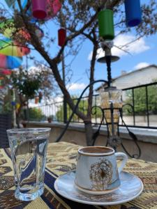 a cup of coffee on a table with a glass at Aysultan Stone House in Uchisar