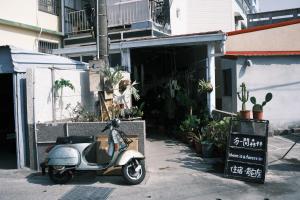 a scooter parked in front of a building with plants at A Forest Homestay in Xiaoliuqiu