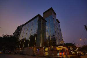 a tall building with glass windows at night at Hotel JRD Exotica in New Delhi