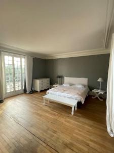 a bedroom with a white bed and a wooden floor at Belle maison dans un village de charme in Moisson