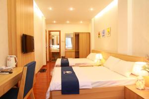 Una habitación de hotel con dos camas y un escritorio. en Little Nha Trang Hotel, en Nha Trang