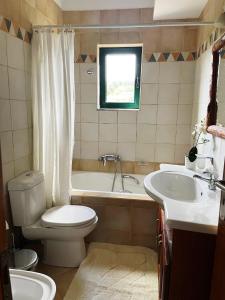 a bathroom with a toilet and a tub and a sink at Olive Villa in Xirokámbion