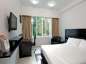 Keys Select by Lemon Tree Hotels, Katti-Ma, Chennai في تشيناي: غرفة نوم بسرير ومكتب وتلفزيون