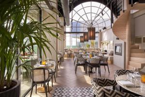 een restaurant met tafels, stoelen en planten bij The Den, 's-Hertogenbosch, a Tribute Portfolio Hotel in Den Bosch