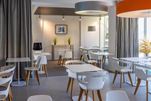 a restaurant with white tables and chairs and windows at Hôtel Riva Art & Spa in Menton