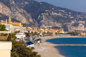 a view of a beach with buildings and mountains at Hôtel Riva Art & Spa in Menton