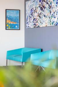 a room with two blue couches and a painting at Hôtel Riva Art & Spa in Menton