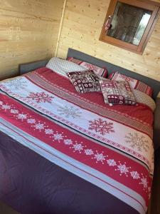 a bed in a cabin with a red blanket and pillows at La Rouloulotte in Durbuy