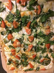 a pizza with tomatoes and spinach on a cutting board at Gasthof zur alten Feuerwache in Bad Hönningen