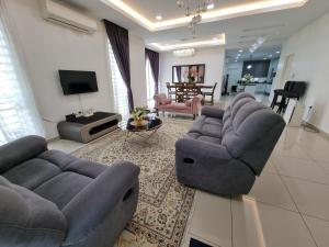 a living room with two couches and a tv at Aluha Homestay Sendayan with Swimming Pool in Labu