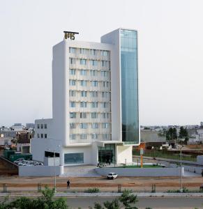 a large white building with a car parked in front of it at Keys Select by Lemon Tree Hotels, Ludhiana in Ludhiana