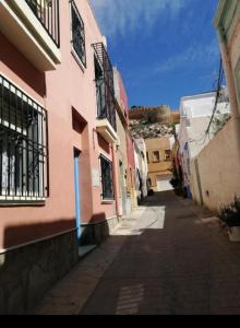 un callejón estrecho con un edificio rosa con ventanas en Santa Clara, en Almería