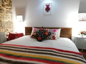 a bed with colorful pillows on top of it at Casa Pedra & Cal in Paredes de Coura