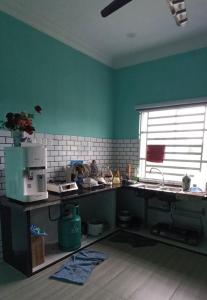 uma cozinha com paredes verdes e uma secretária com uma janela em HOMESTAY BY ZIKRY em Kota