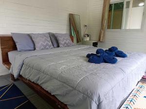 Una cama con peluches azules encima. en บ้านชายดอย Glamping ดอยแม่แจ๋ม cheason ,Muangpan, Lampang en Ban Mai