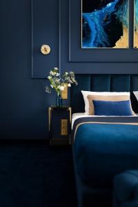 Un dormitorio azul con una cama y un jarrón con flores en IBB Hotel Grand Hotel Lublin en Lublin