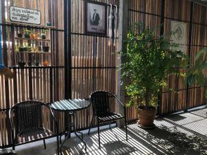 a patio with two chairs and a table and a plant at Suandok History House in Chiang Mai