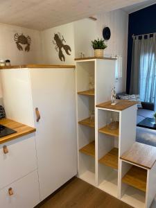 a kitchen with white cabinets and wooden shelves at Tiny House Stever im PIER9 Tiny House Hotel in Hamm