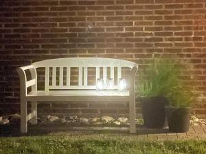 a white bench sitting in front of a brick wall at 9 person holiday home in Harbo re in Harboør