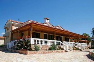 una casa con porche blanco y barandilla blanca en Villa Kostoula, en Karavomylos