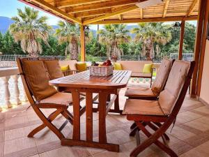 una mesa de madera y sillas en un patio con palmeras en Villa Kostoula, en Karavomylos