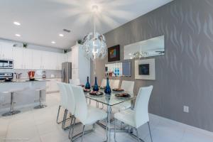 uma sala de jantar com uma mesa de vidro e cadeiras brancas em Solara Resort - 5 Bed 4,5 Baths TOWNHOME em Orlando