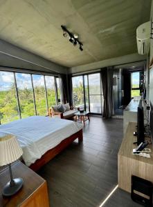 a bedroom with a bed and a living room with windows at Lin's Forest in Hengchun