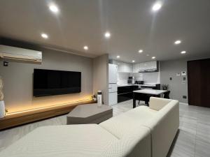 uma sala de estar com um sofá branco e uma televisão de ecrã plano em Platinum.Kiyomizu em Giommachi