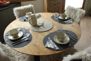 uma mesa de madeira com pratos, chávenas e utensílios em Chesa Freihof em Celerina