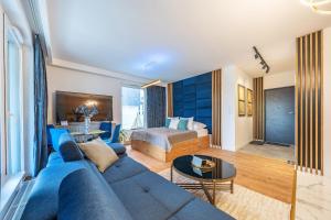 a living room with a blue couch and a bed at Glow Apartments, Letnica - Apartamenty Przystań Siódme Niebo in Gdańsk