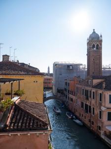 - une vue sur un canal dans une ville dotée d'une tour d'horloge dans l'établissement Foscà Venice Rooms, à Venise