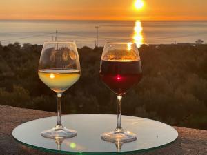 two glasses of wine sitting on a plate with the sunset at Stylish Manihaus for a romantic adventure in Stoupa
