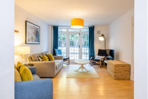 a living room with a couch and a table at Modern apt near gardens with large decking area - Vivre Retreats in Bournemouth