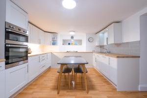 una cucina con armadietti bianchi e un tavolino di Modern apt near gardens with large decking area - Vivre Retreats a Bournemouth