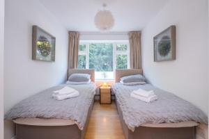 two beds in a room with a window at Modern apt near gardens with large decking area - Vivre Retreats in Bournemouth