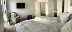1 dormitorio con 1 cama blanca grande y TV en 49 1 N Nordkoje, en Wangerland