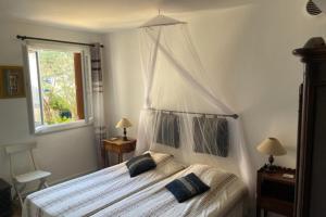 een slaapkamer met een groot bed met een baldakijn bij Charming apartment overlooking the lake city in Grimaud