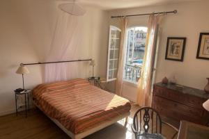 een slaapkamer met een bed, een dressoir en een raam bij Charming apartment overlooking the lake city in Grimaud