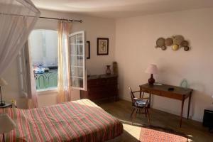 een slaapkamer met een bed, een bureau en een raam bij Charming apartment overlooking the lake city in Grimaud