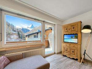 a living room with a large window and a tv at Eagle apartment with splendid and direct view of the Matterhorn in Zermatt