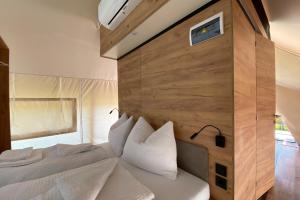 1 dormitorio con cama blanca y pared de madera en Comfort Safarizelt direkt am Ossiachersee en Steindorf am Ossiacher See
