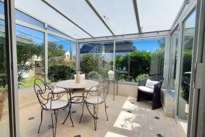 Maison côte sauvage classement 3 في كويبيرون: حديقة شتوية مع طاولة وكراسي ونوافذ زجاجية