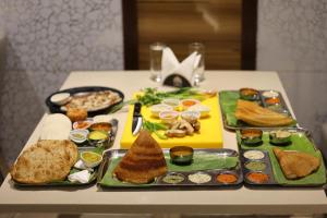 a table with plates of food on a table at Hotel Woodside Prestige in Tirupati