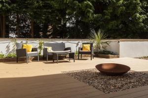 een groep stoelen en een kom op een patio bij Modern apt near gardens with large decking area - Vivre Retreats in Bournemouth