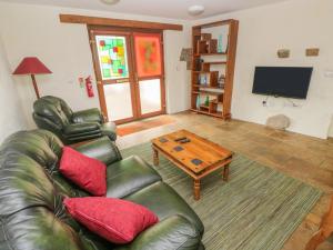 a living room with a leather couch and a coffee table at Nook in Narberth