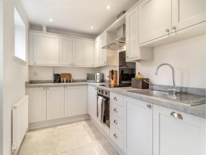 a white kitchen with white cabinets and a sink at Vancouver View in King's Lynn