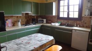 una cucina con armadi verdi e un tavolo di Maison de vacances a Trévières